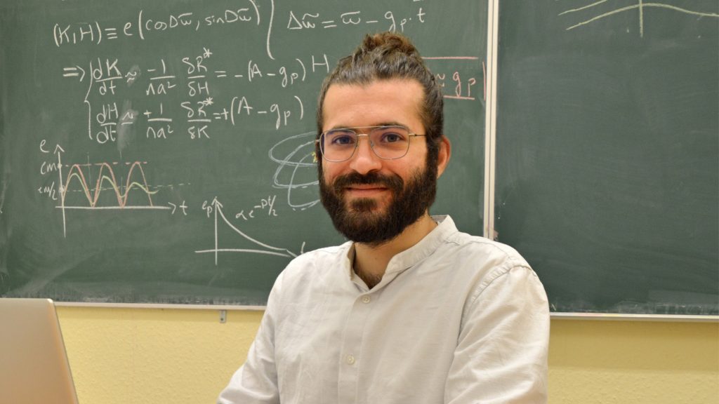 Antranik Sefilian in front of a blackboard smiling at camera.
