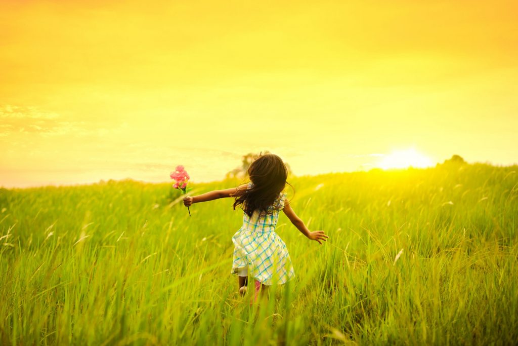 Small child runs away from camera in a field.