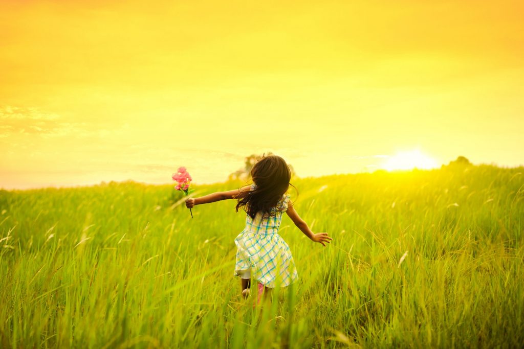 Small child runs away from camera in a field.
