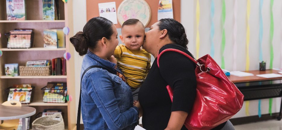 Two women hold small child between them.