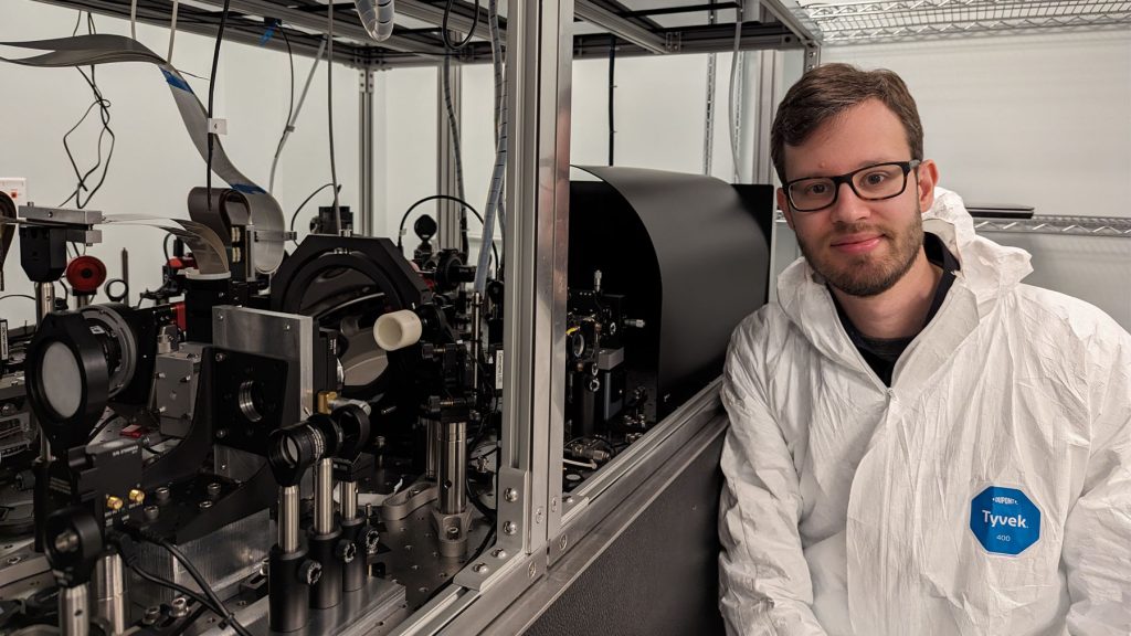 Emiel Por in a lab, standing and smiling at camera.