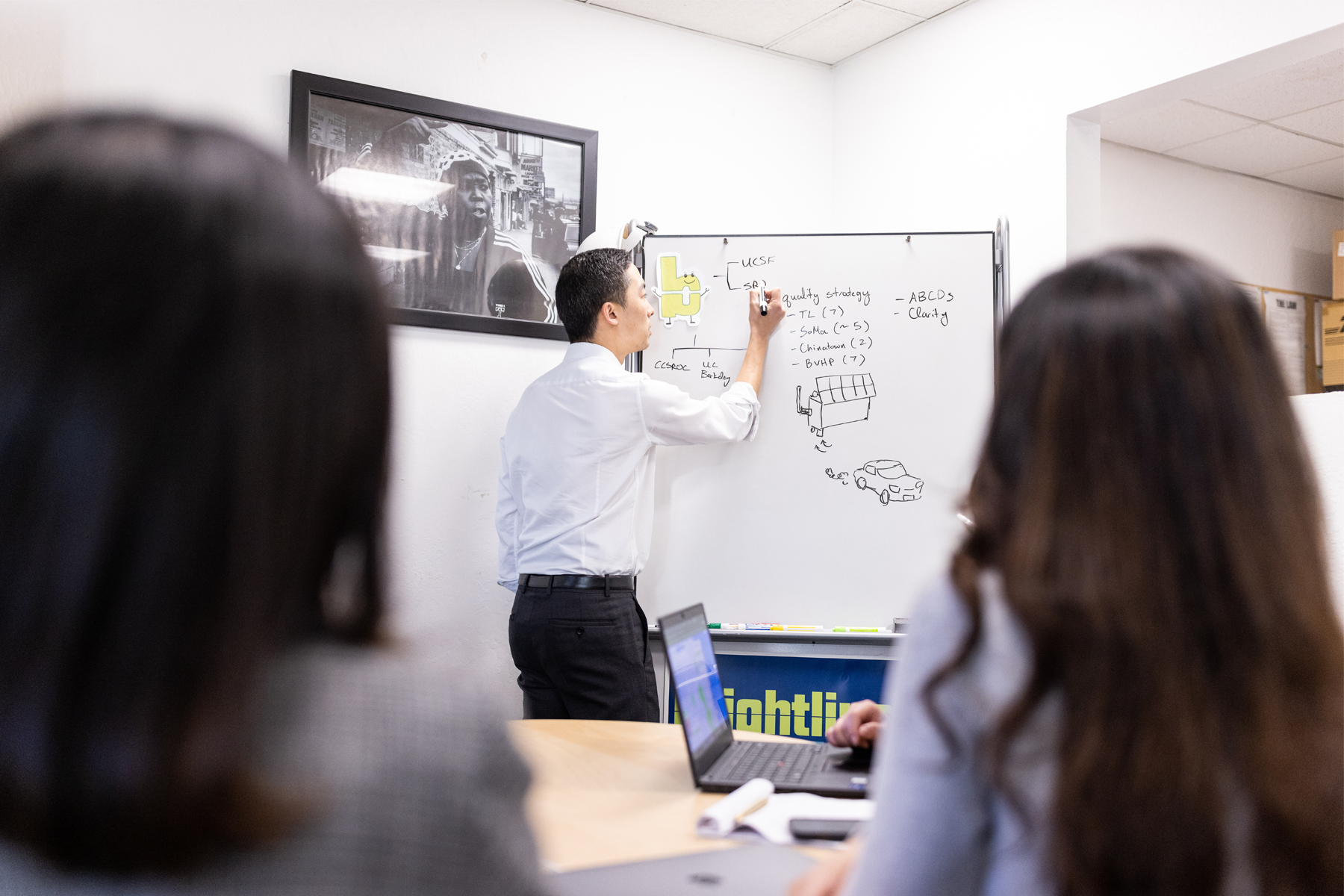 A man writing on a whiteboard in a conference room.