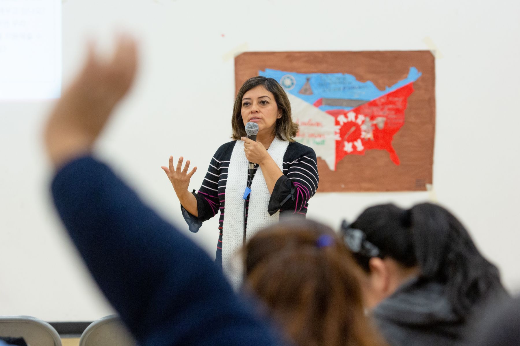 A woman with a microphone speaking to a crowd.