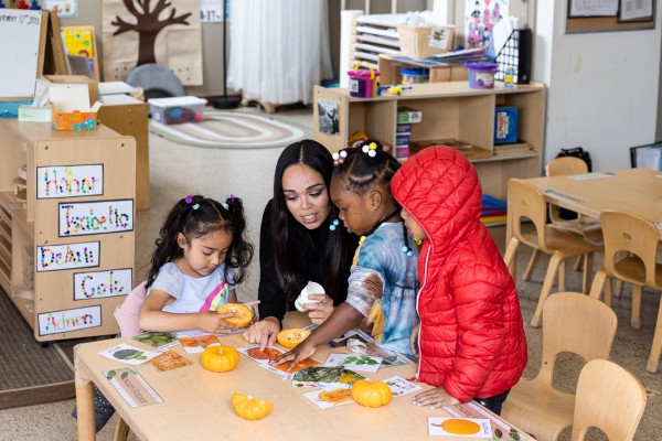 Teacher plays with three young children at a table.