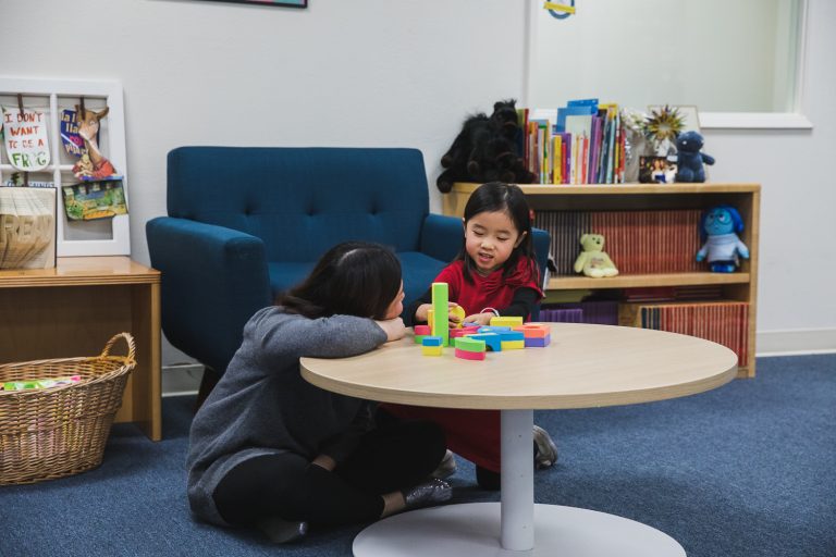 Woman plays with building blocks with young girl.